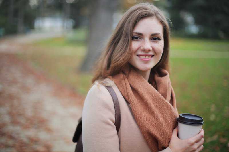 woman outside with coffee and sweater | Top Dentist and Periodontist for root canals, veneers, dental fillings, wisdom teeth extractions, gum disease therapy, and more | Houston 77077